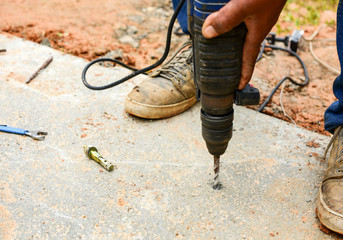 People are using electric drill,He drilled concrete to put steel anchor.