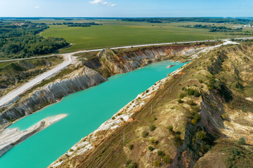Abandoned mountain quarry. The mine workings are filled with water of a deep blue color. Aerial view