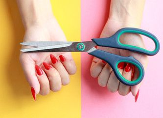 Fun minimal concept. Woman hands with scissors. Top view. Pastel colours background. Trendy colors.