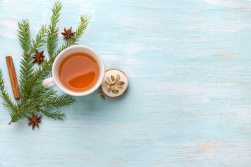 A cup of tea with fragrant honey Christmas gingerbreads with glaze and nuts, with Christmas tree branches and spices on a light blue background, free space, top view, horizontal
