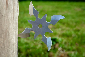 Shuriken (throwing star), traditional japanese ninja cold weapon stuck in wooden background