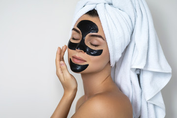 Young and beautiful woman with black peel-off mask on her face