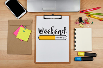 Weekend loading text on white sheet and office supplies on wooden table