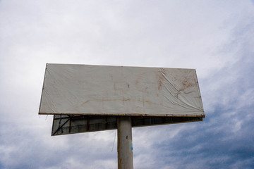 Empty commercial billboard, storm clouds on the background on early autumn day.