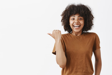 Waist-up shot of surprised pleased and impressed happy attractive dark-skinned female in brown...