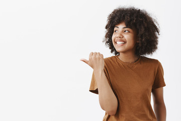 Girl showing where she bought cool t-shirt. Portrait of joyful dreamy and carefree young african...