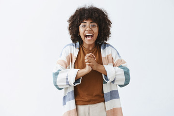 Enthusiastic active and carefree dark-skinned optimistic girl in glasses and stylish outfit...