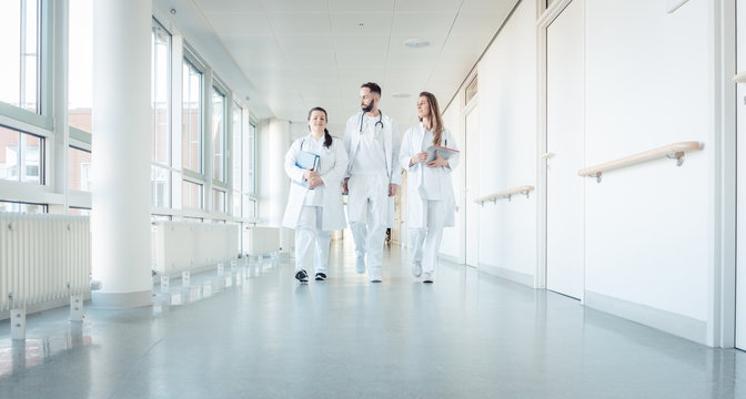 Doctors, two women and a man, in hospital walking down the corridor