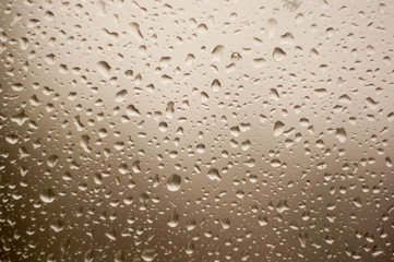 raindrops on window glass on background of cloudy sky