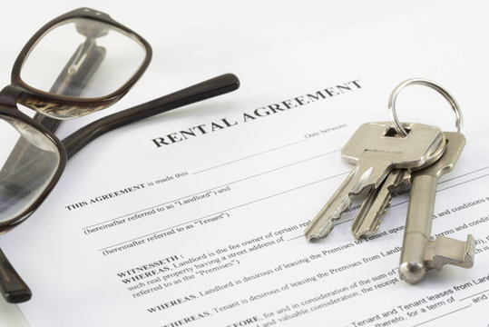 Rental Agreement Document With A Set Of House Keys And Glasses