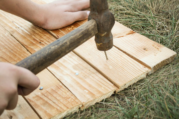 master hammer nail into a wooden Board on the grass