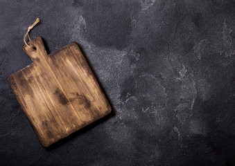 Fototapeta premium Vintage wooden cutting board on top of black stone kitchen stone background.Kitchen cooking concept. Top view. Space for text.