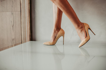 Close up fashion feet wearing fashion beige shoes on high heels inside. Style concept