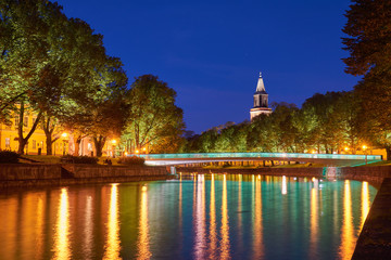  The night view of Aura river in Turku, Finland with a clock tower of cathedral and bridge on a background.                  