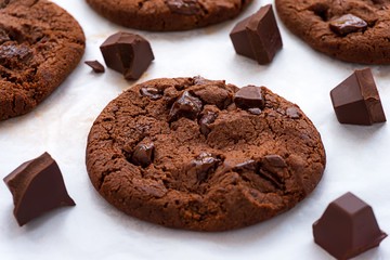 Soft baked chocolate cookies and chocolate bar on baking paper