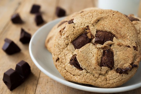 Close up image of chocolate bar and cookies and a cup of milk