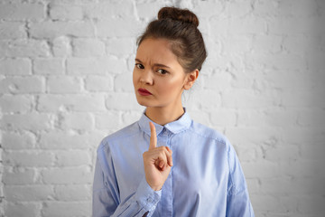 Portrait of displeased attractive young woman teacher with hair bun frowning and holding fore...