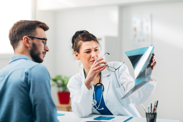 Portrait of Woman Doctor at her Medical Office Looking at X-Ray with Patient