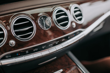 Close up dashboard with contemporary speedometer and indicator with menu buttons in wooden interior...