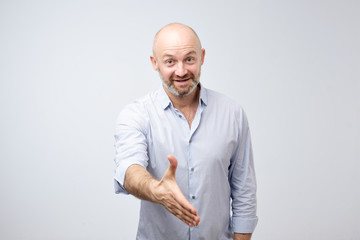 Friendly-looking attractive european man giving a hand in hello gesture while smiling cheerfully
