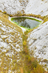 Small lake in the white mountains and hills. Abandoned desert view. Phosphogypsum stack of chemical production wastes and oil.  Industrial atmospheric emission of factories and environmental pollution