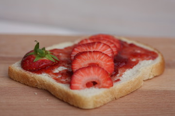 Slice of bread with jam and strawberries.