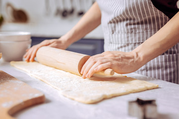 Dough. Beautiful hands of a young woman placed on the wooden rolling pin during the process of making cookies