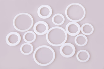 White hydraulic and pneumatic o-ring seals of different sizes scattered a white background. Rubber rings. Sealing gaskets for hydraulic joints. Rubber sealing rings for plumbing. Top view