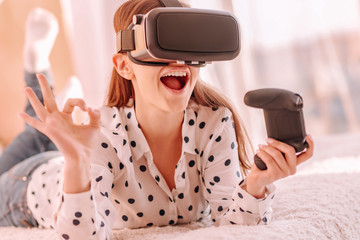 Everything okay. Smiling young woman in VR glasses showing okay by her hand playing computer games