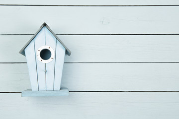 Blue wooden bird house on a blue wooden background with copy space