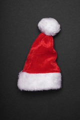 santa claus hat christmas decoration on black paper background with copy space