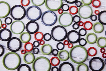 Black, red and gre hydraulic and pneumatic o ring seals of different sizes scattered a white...