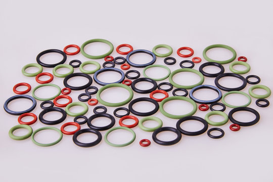 Black, red and gre hydraulic and pneumatic o-ring seals of different sizes scattered a white background. Rubber rings. Sealing gaskets for hydraulic joints. Rubber sealing rings for plumbing. Top view