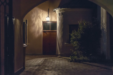 Courtyard in an old historic house, night, the lantern shines over the door