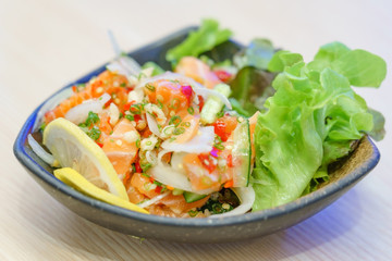 Salmon sashimi in spicy hot sauce. Mix Japanese and Thai food between Japan salmon sashimi and Thai herb in Japanese restaurant.