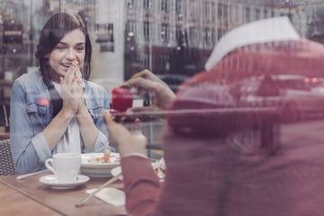 Feeling happiness. Charming female person keeping smile on her face and holding hands together while looking forward