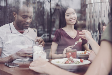 Collective dinner. Attentive dark-skinned man bowing head while going to drink coffee