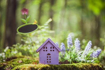 fabulous, toy house, the colors of lavender with a sign for inscription,  against the backdrop of a fairy forest. Concept cozy home, cozy world.