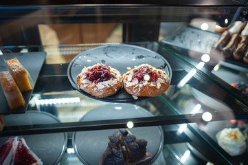 Cakes and buns in the coffee house. Cakes with berries and cream, nuts and fruits.