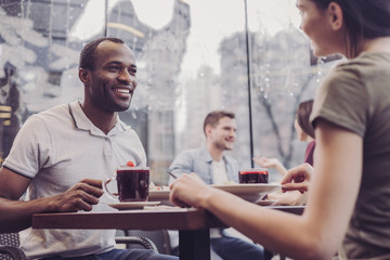 Pleasant talk. Joyful young man sitting in cafe and discussing business idea