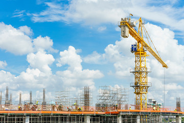 Construction site. Construction cranes and high-rise building under construction against blue sky.