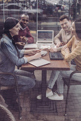 Work in team. Cheerful brunette female sitting in semi position while listening to her partners