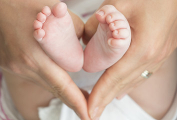 Obraz na płótnie Canvas baby feet in mother hands - hearth shape