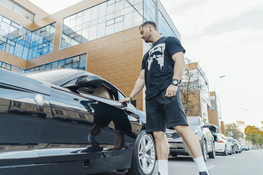 Distant Plan Of Young Attractive Man Getting Out Of The Black Car.