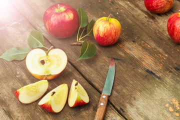 Red apple sliced and knife on old wooden table