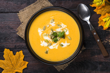 Pumpkin cream soup on dark wooden table.