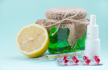 Green cough syrup , pills, thermometer,  lemon, nasal drops.  Healthcare, treatment and medicine concept