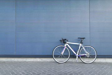 Fototapeta na wymiar White highway bike stands on the background of a blue wall. Sports concept. Cycling Concept