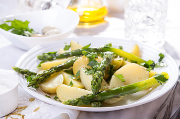 Boiled potato with grilled green asparagus on white plate over on white background.