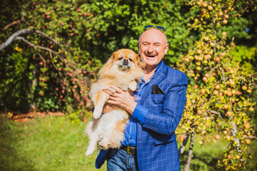 Senior man with his pet little red pekingese dog at home yard. American mature man with a dog. Concept of Life animals and human 